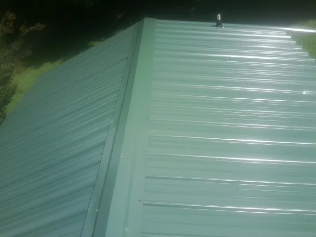 New green metal panels meeting at the ridge of a roof — Flat Roof Repair work by our crew in Natrona Heights