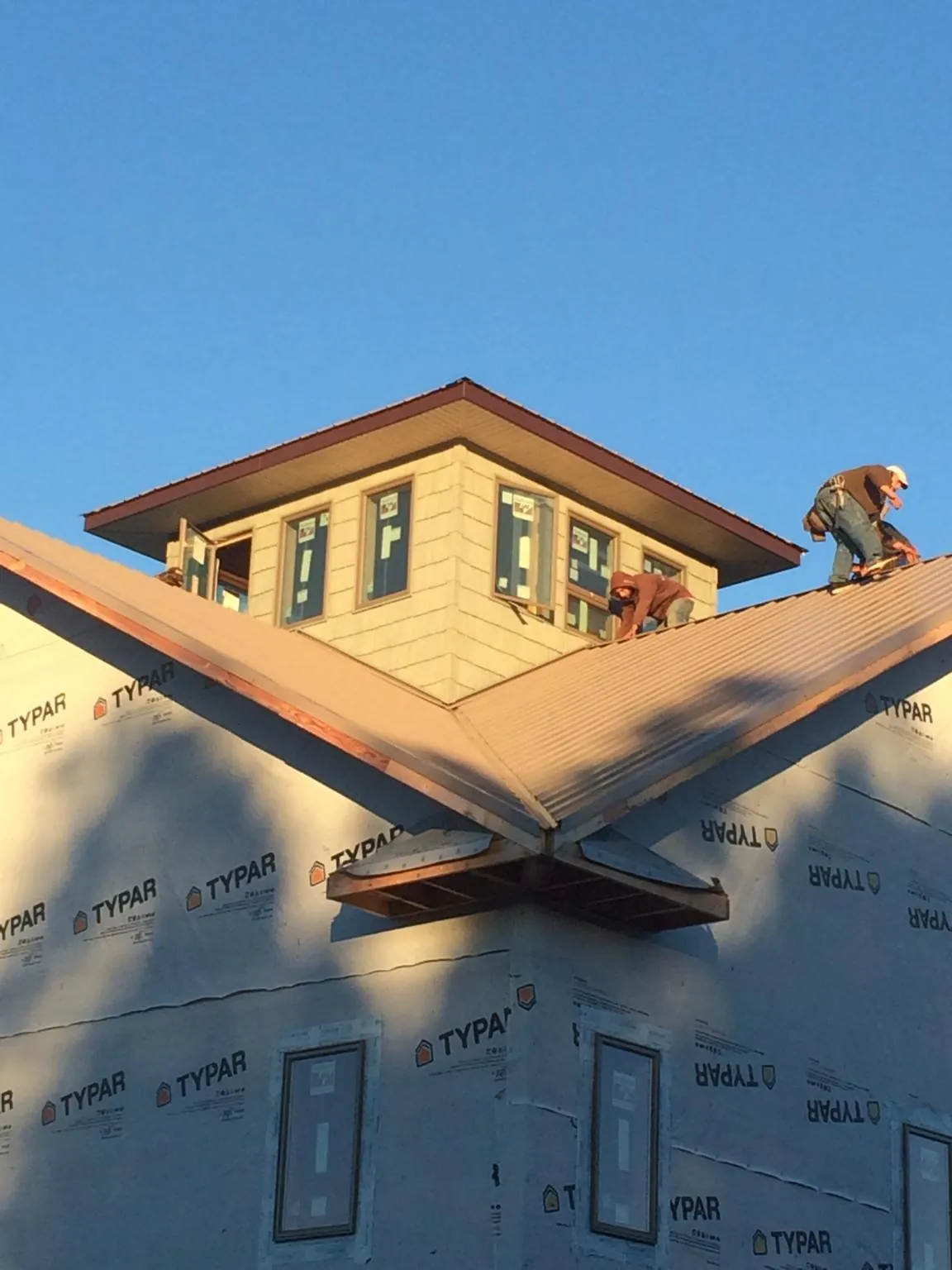 Roofers working around a rooftop cupola on a new metal roof at sunset — Roof Waterproofing in Natrona Heights by Roofing Brothers